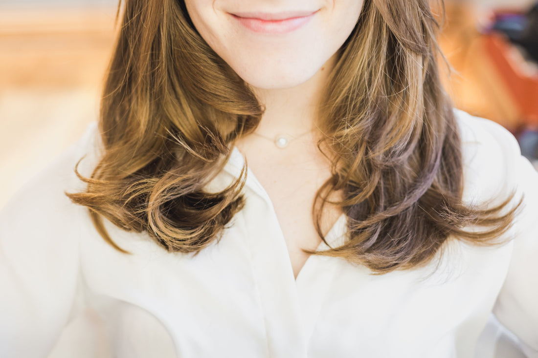 Mujer sonriendo con cabello largo y suelto, mostrando productos dermocosméticos para piel sensible