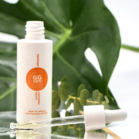 Botella de aceite reparador oncológico de GGCare con gotero en fondo verde natural