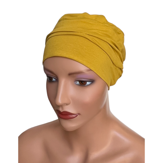 Turbante oncológico bambú en color mostaza, cómodo y elegante para uso diario.